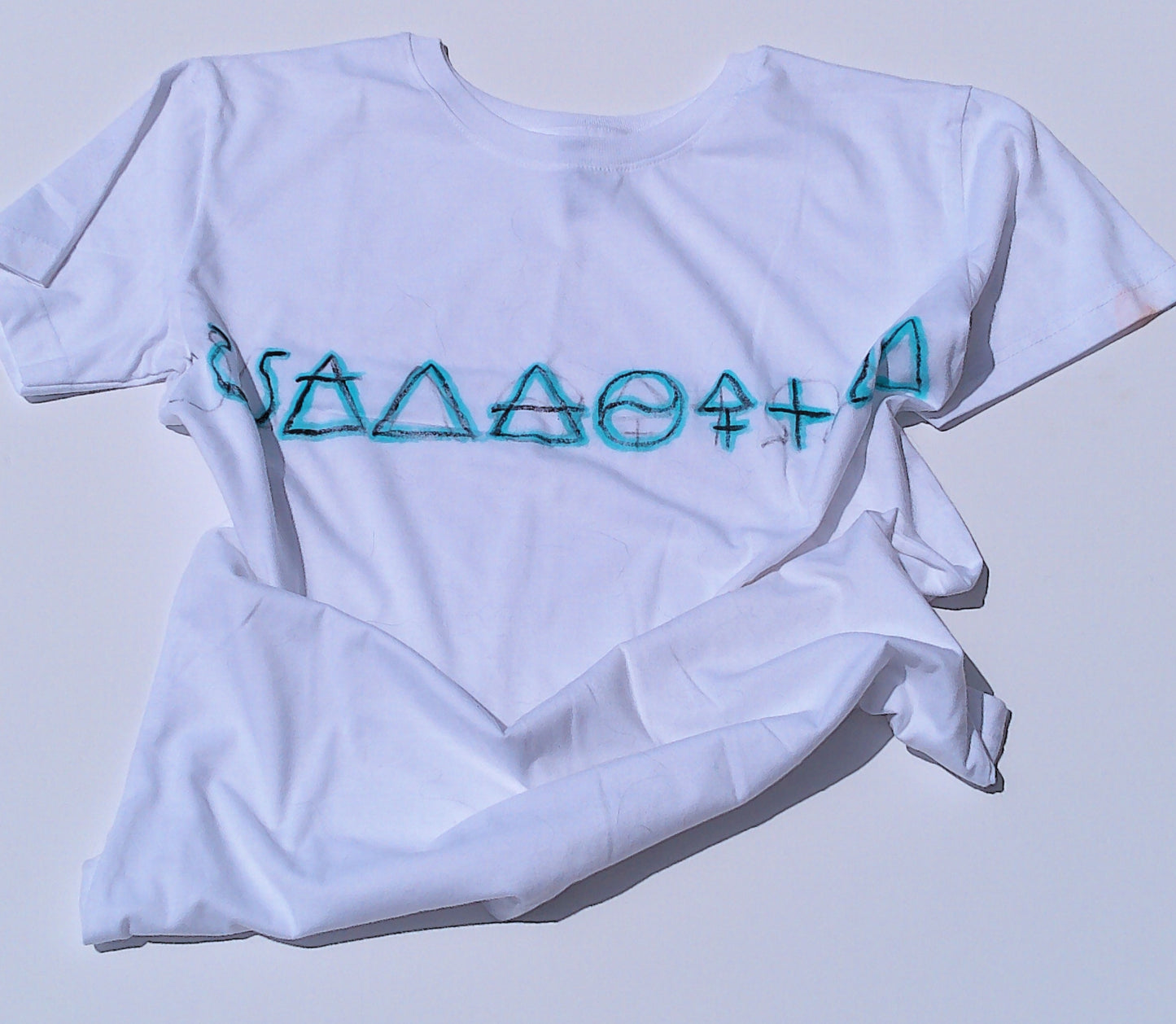 White t-shirt with blue geometric design on a light gray background