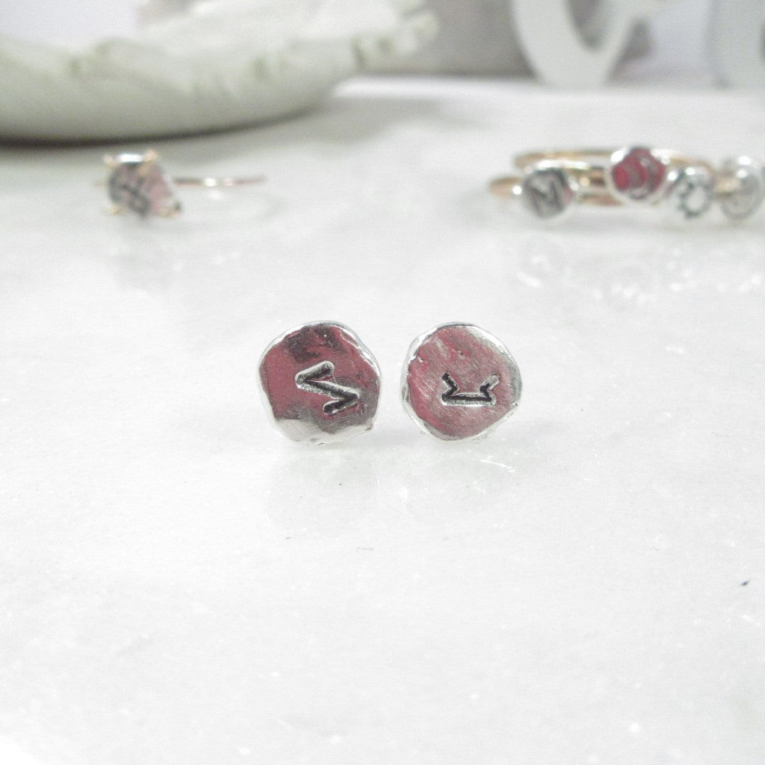 A pair of silver nugget post earrings with oxidized runic symbols, displayed on a white surface.