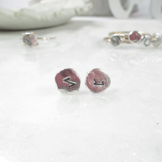 A pair of silver nugget post earrings with oxidized runic symbols, displayed on a white surface.