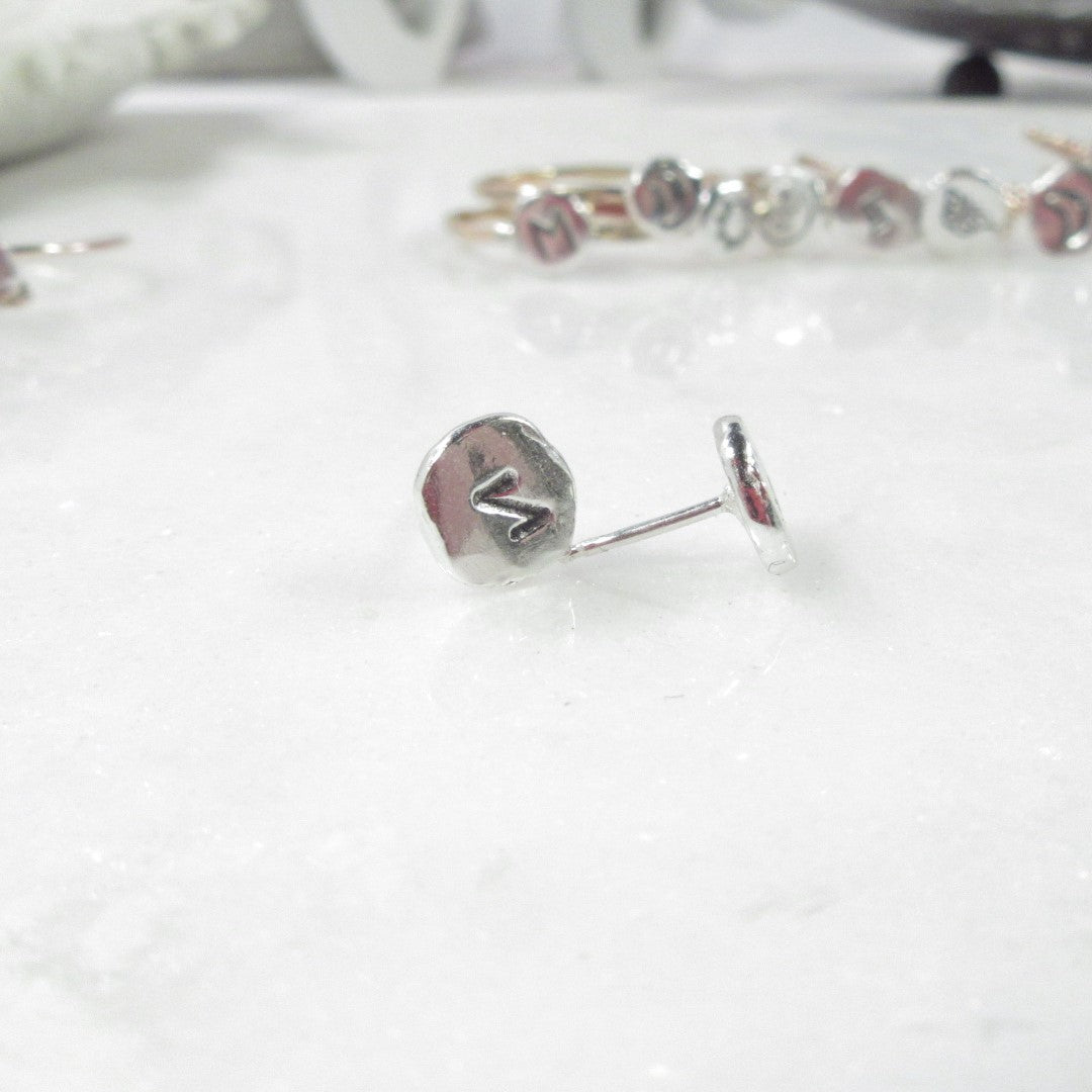 A pair of nugget post earrings with oxidized runic symbols, displayed on a white surface.