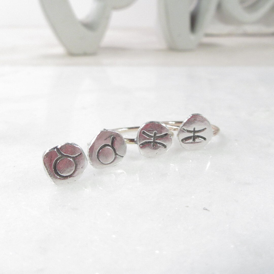 post earrings and tiny hoop earrings with astrology imprints on a white background