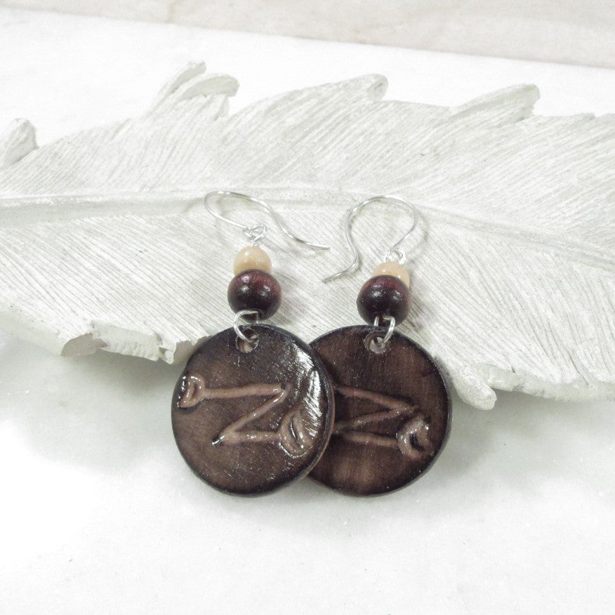 Pair of earrings with brown circular charms and beads on a white background