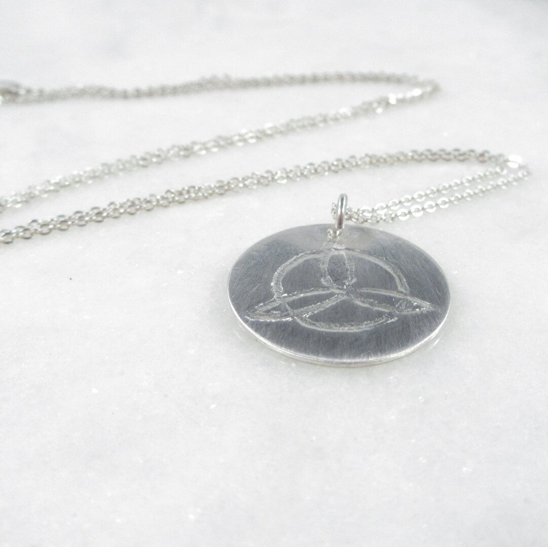 Silver necklace with a round pendant on a white background