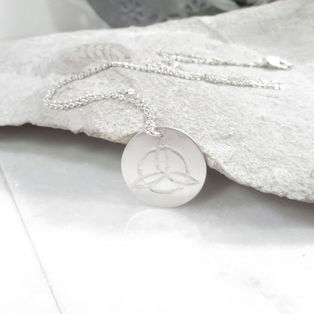 Silver necklace with a round pendant on a stone background