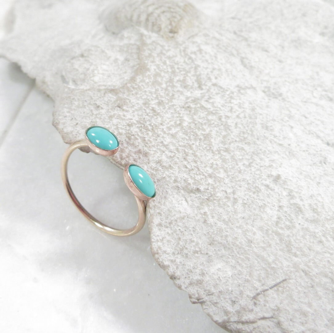 Ring with turquoise stones on a textured white surface