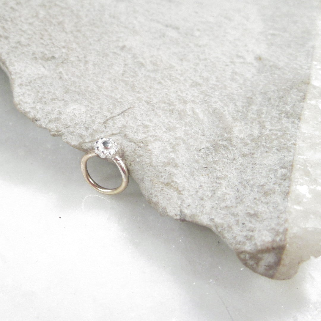 Flower tragus ring on a textured stone surface