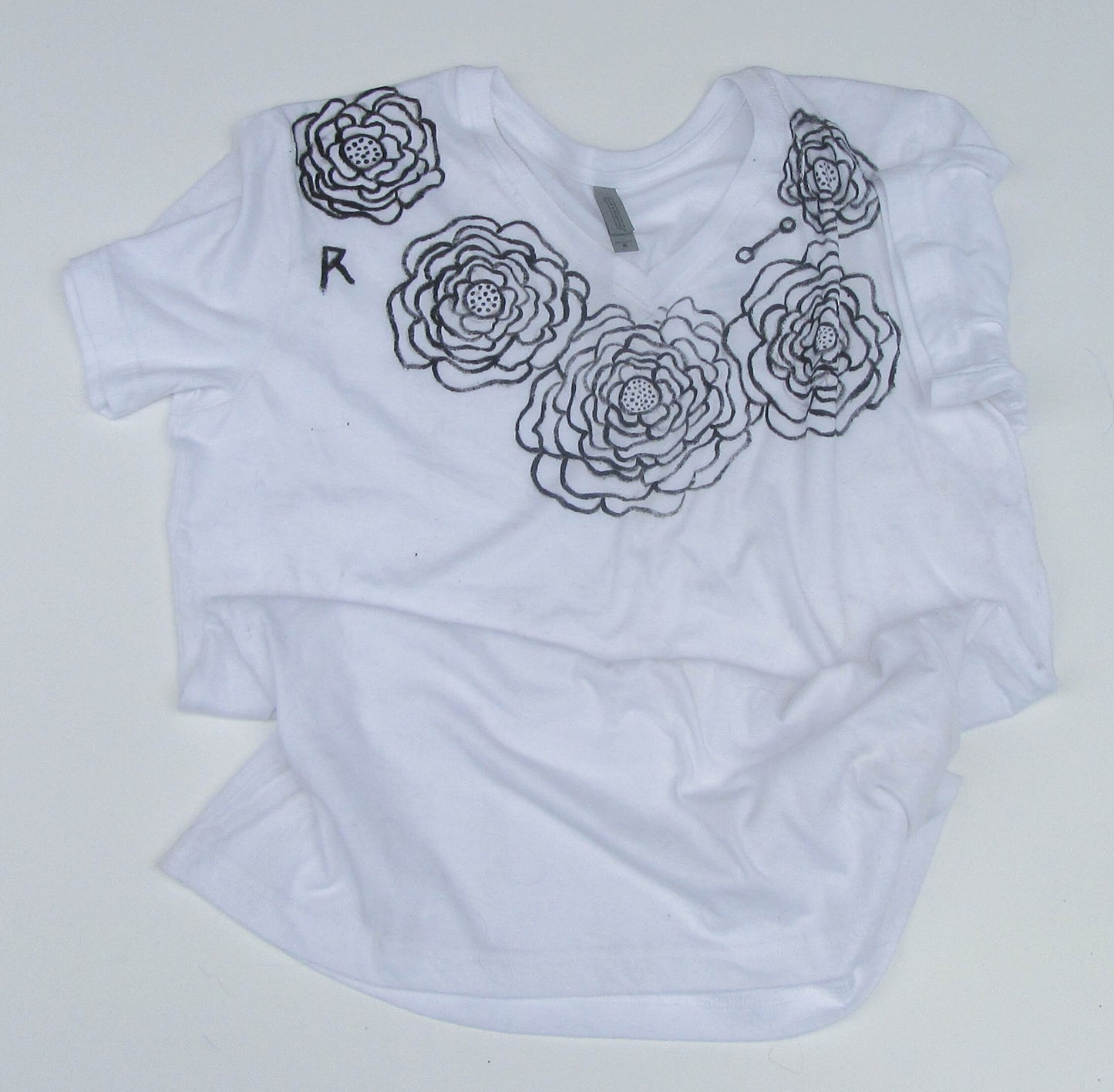 White t-shirt with black floral designs on a white background