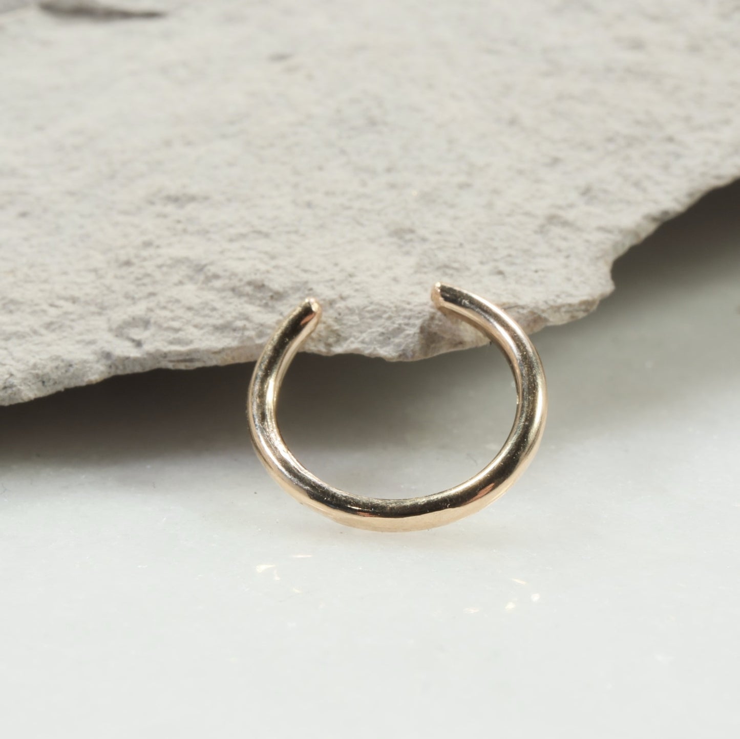 Gold nose ring on a stone surface