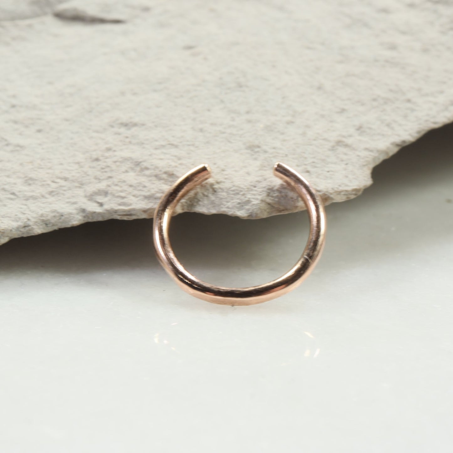 Rose gold nose ring on a stone surface