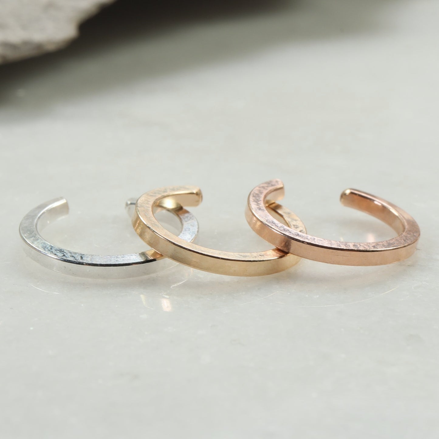 Three gold hoop earrings on a light gray background