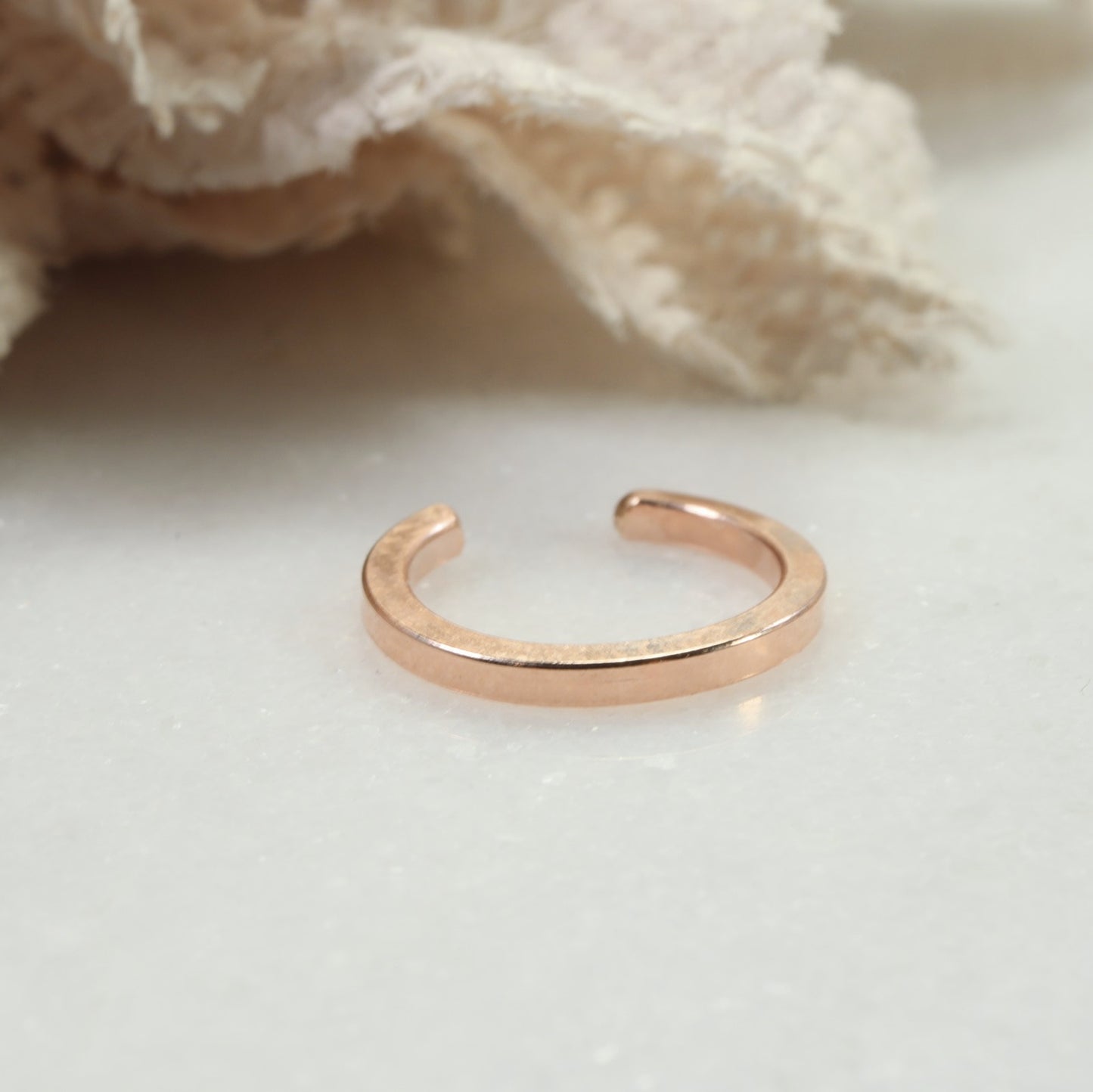 Rose gold open ring on a light background
