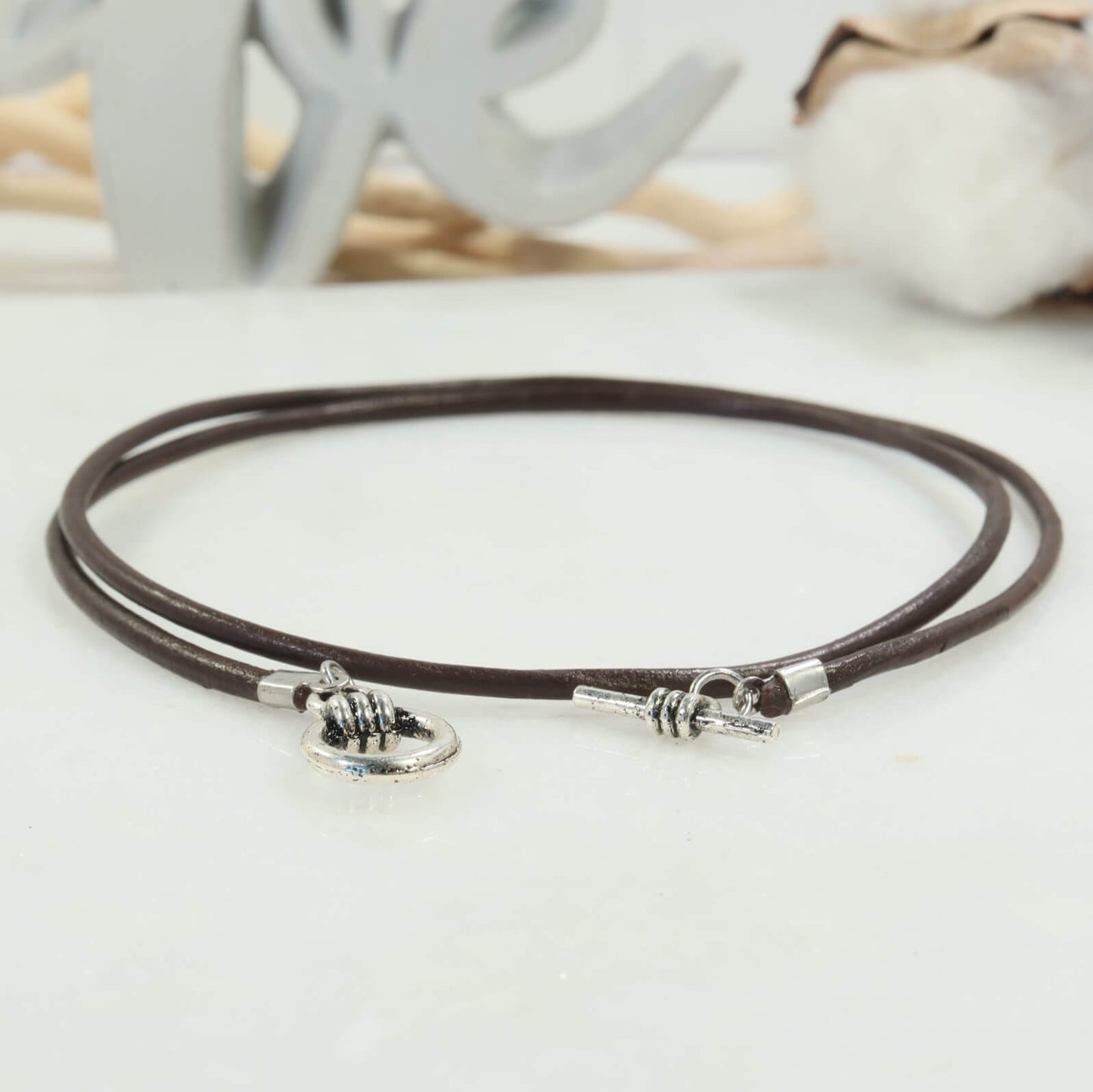 Brown leather necklace with silver clasp on a light surface
