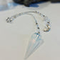 A crystal pendulum with a large faceted pale blue quartz point, suspended from a beaded chain with silver-toned star and moon charms.