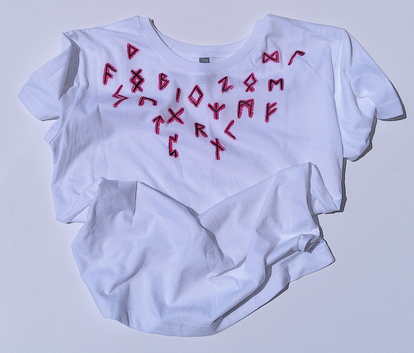 White t-shirt with red runes on a light gray background
