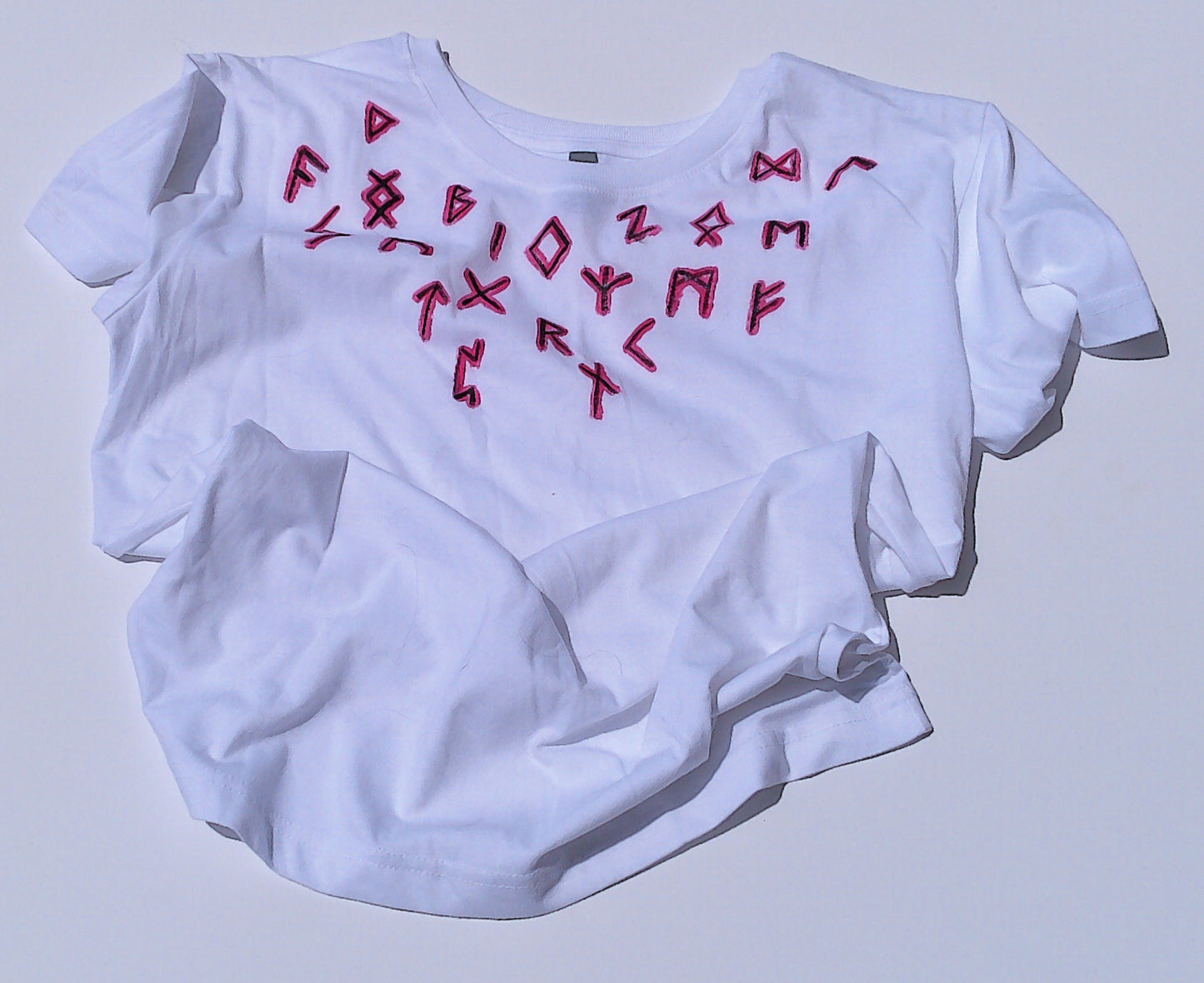 White t-shirt with red rune symbols on a light gray background