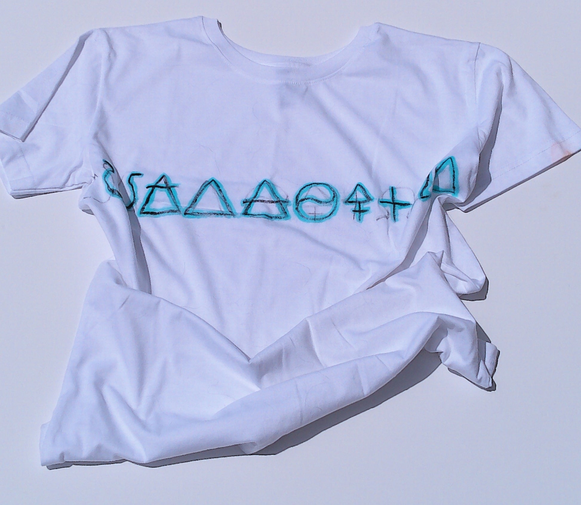 White t-shirt with blue geometric design on a light gray background