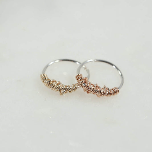 two silver earrings with gold and pink gold wraps on a white background