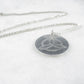 Silver necklace with a round pendant on a white background