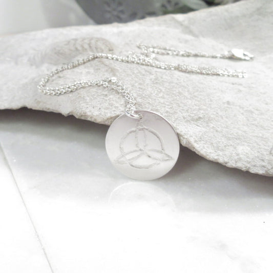 Silver necklace with a round pendant on a stone background