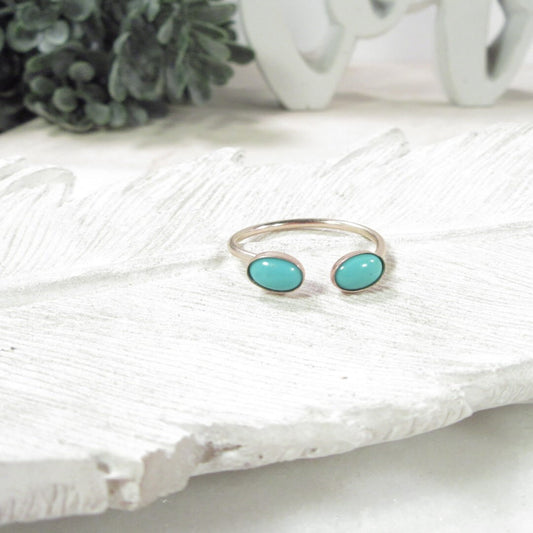 Gold ring with turquoise stones on a textured white surface