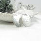 Silver earrings on a white surface with a blurred background
