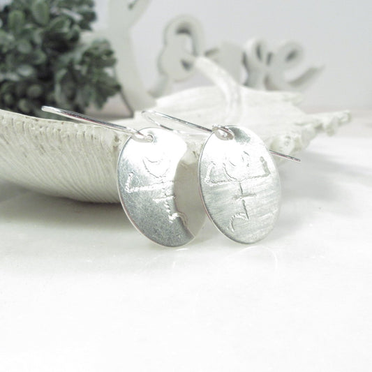 Silver earrings on a white surface with a blurred background