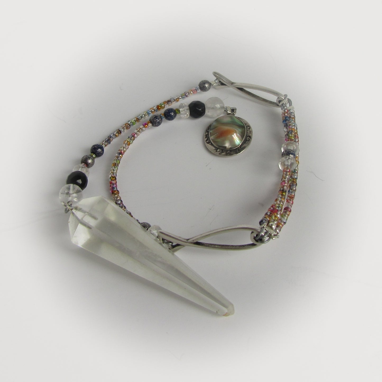 Crystal point with beaded pendulum on a white background