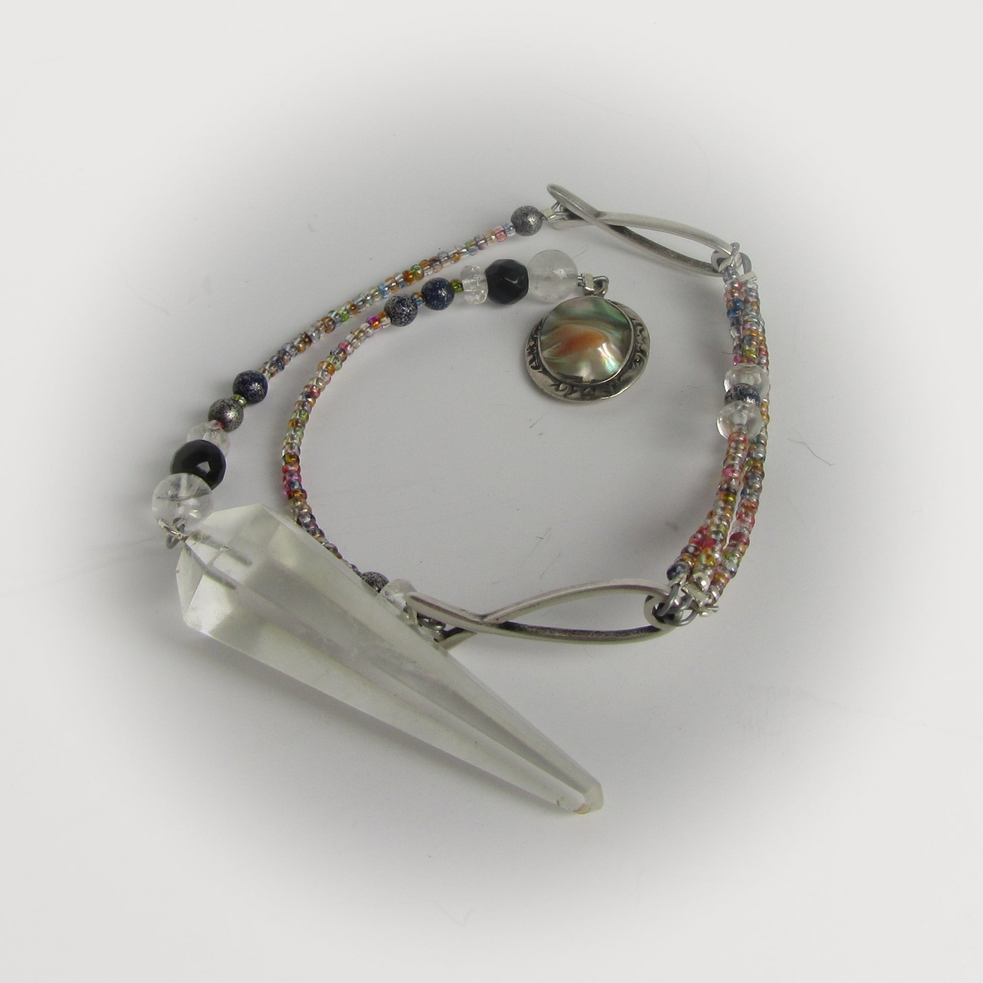 Crystal point with beaded pendulum on a white background
