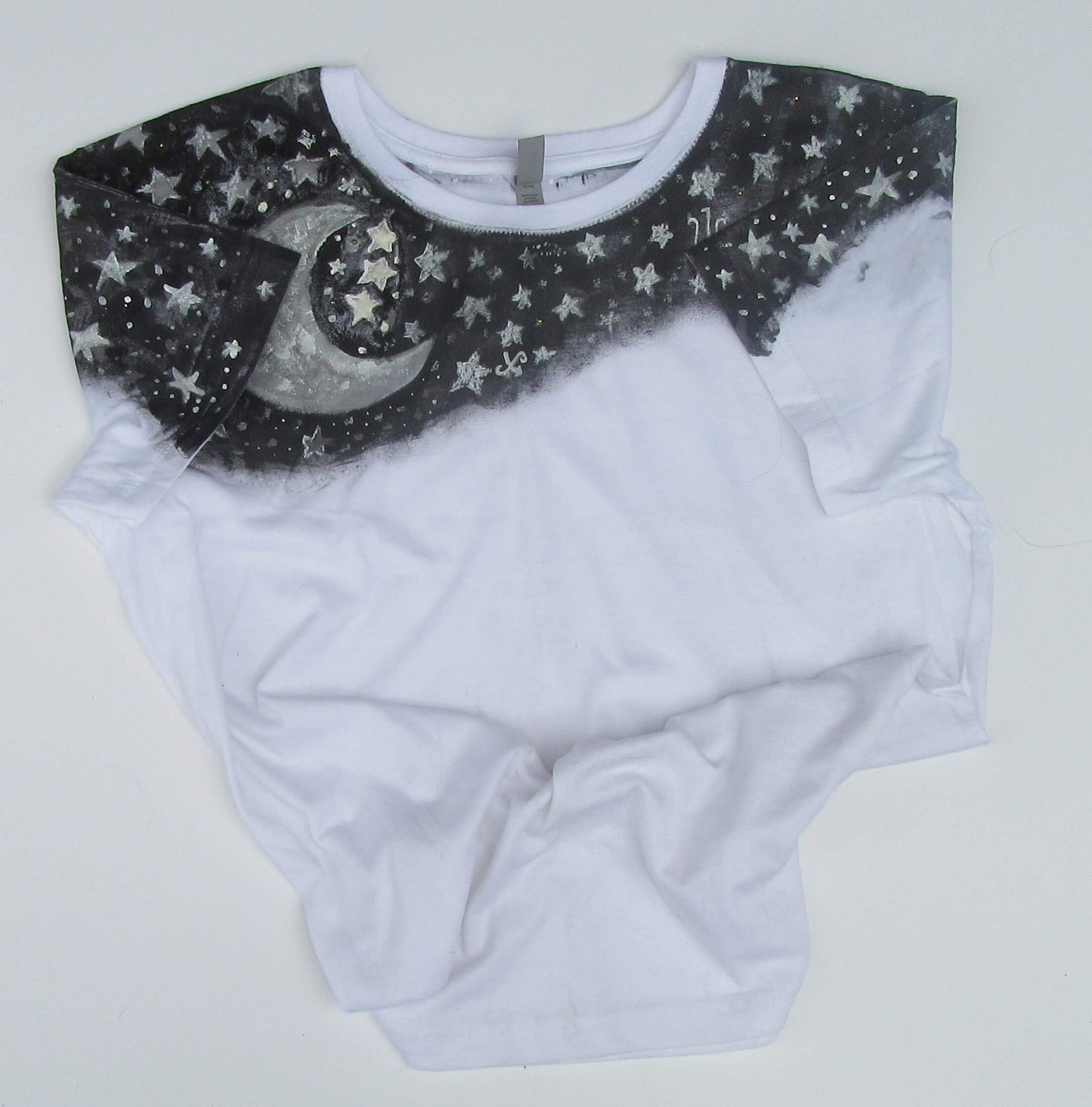 White t shirt with black collar featuring star and moon design on a light gray background