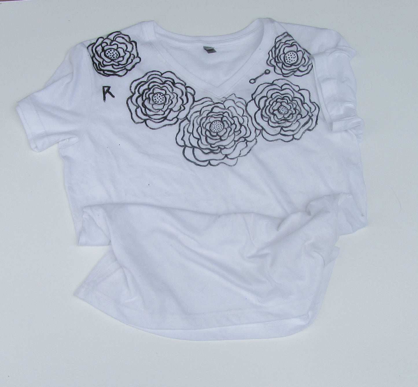 White t-shirt with black floral designs on a white background