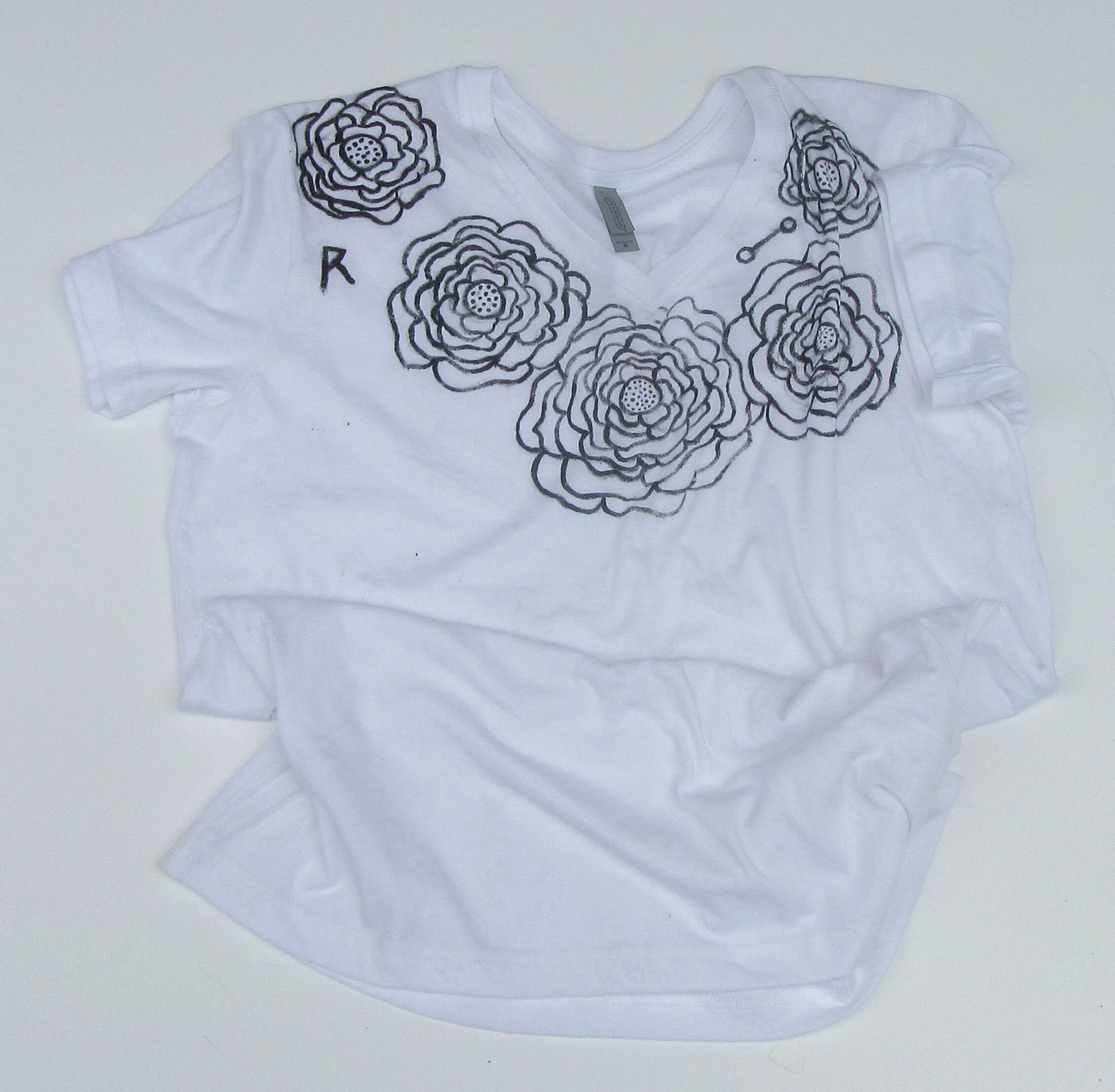 White t-shirt with black floral designs on a white background