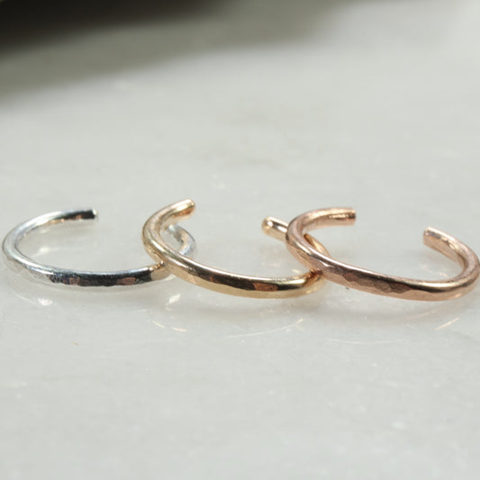 Three gold and silver open rings on a light background