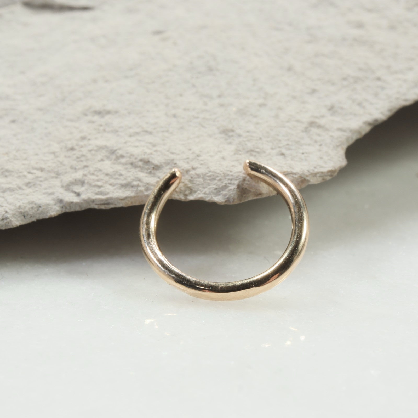 Gold nose ring on a stone surface
