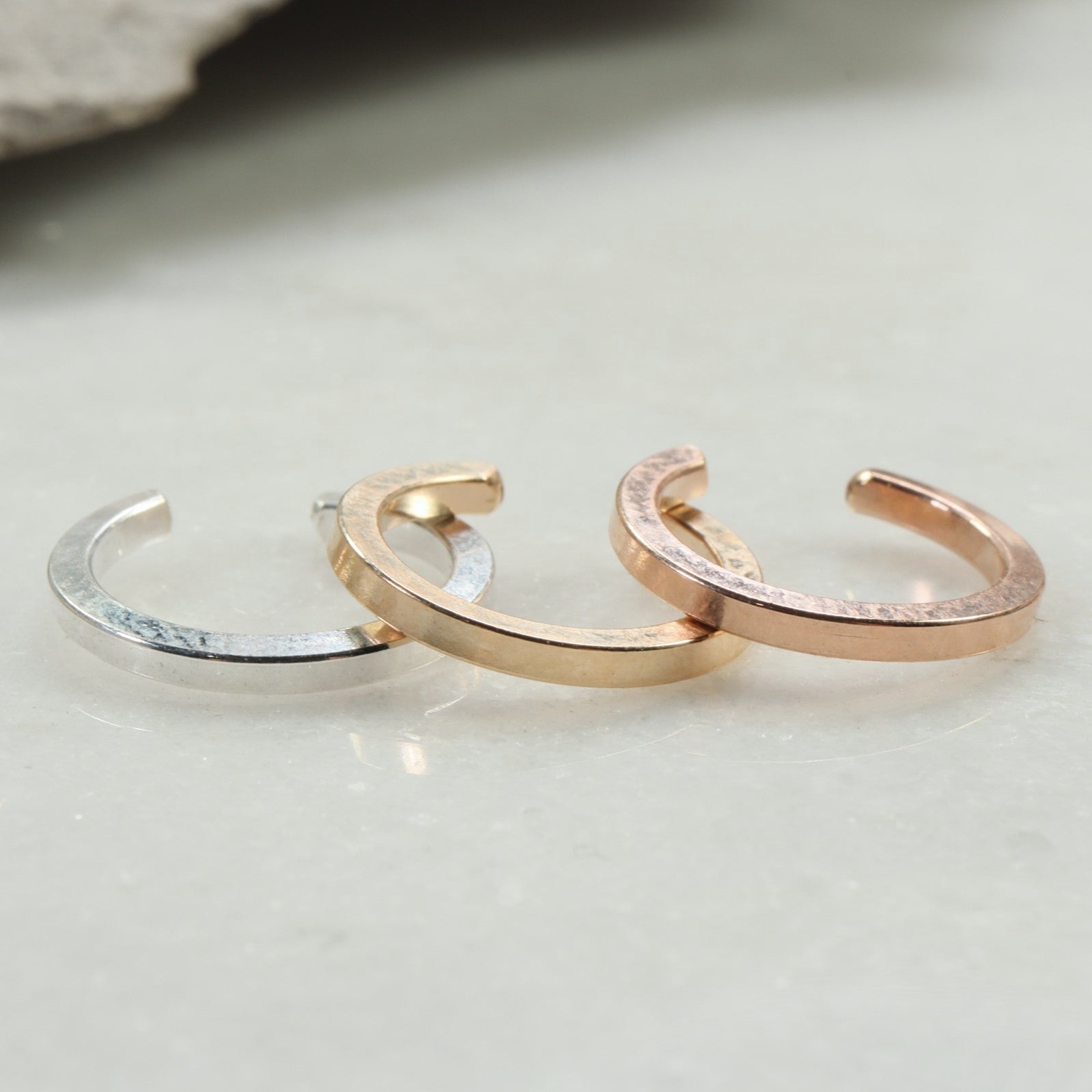 Three gold hoop earrings on a light gray background
