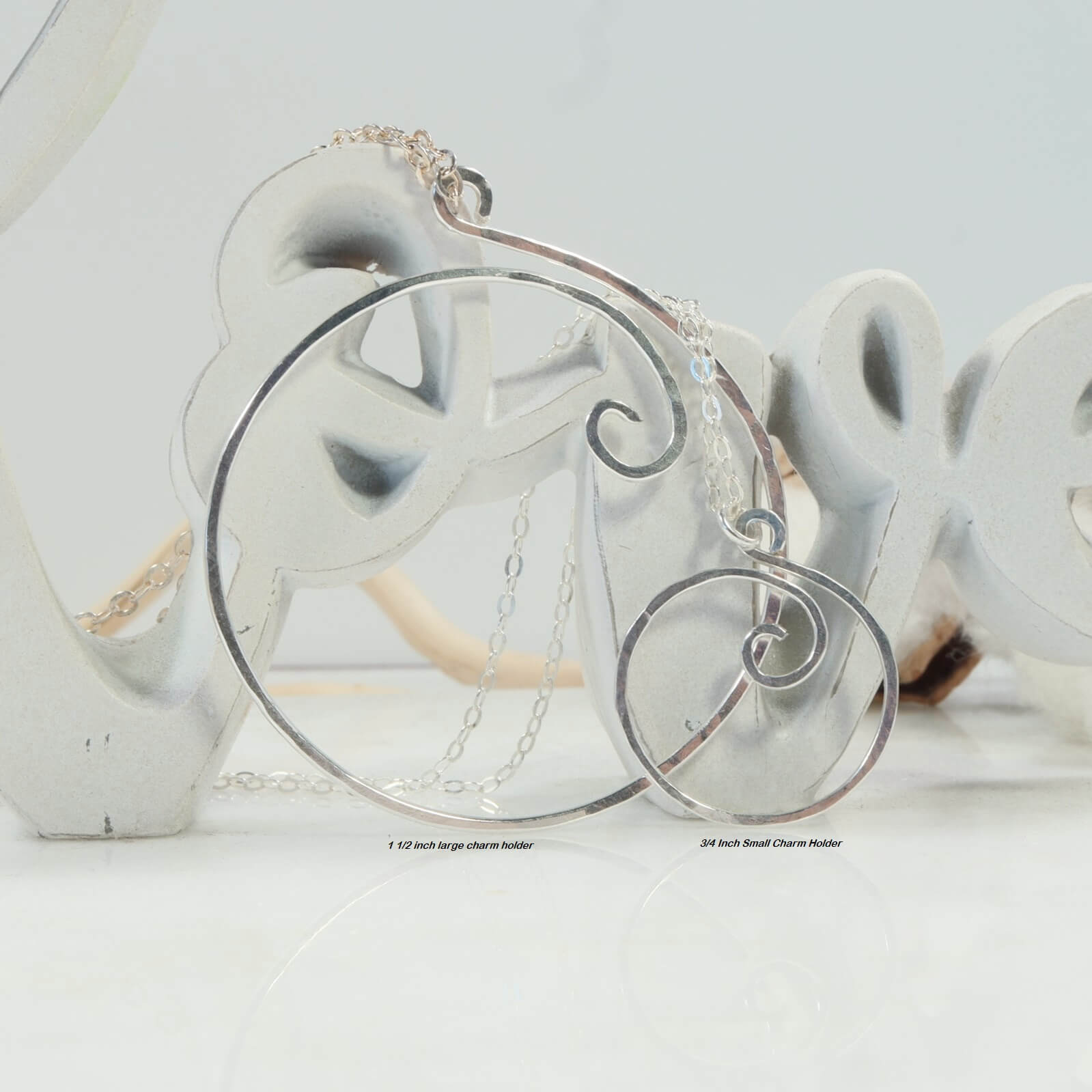 Large charm holder next to small charm holder necklace